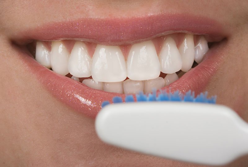 A woman is brushing her teeth with a toothbrush