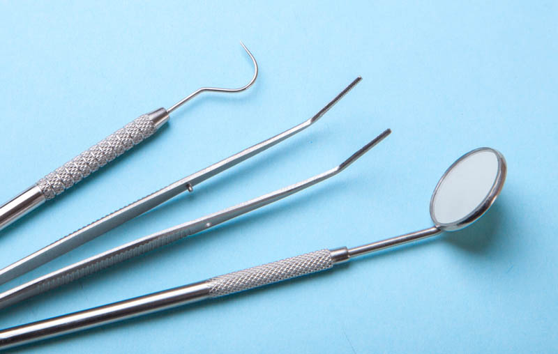Dental instruments. Dental mirror, probe hook, tweezers on blue background