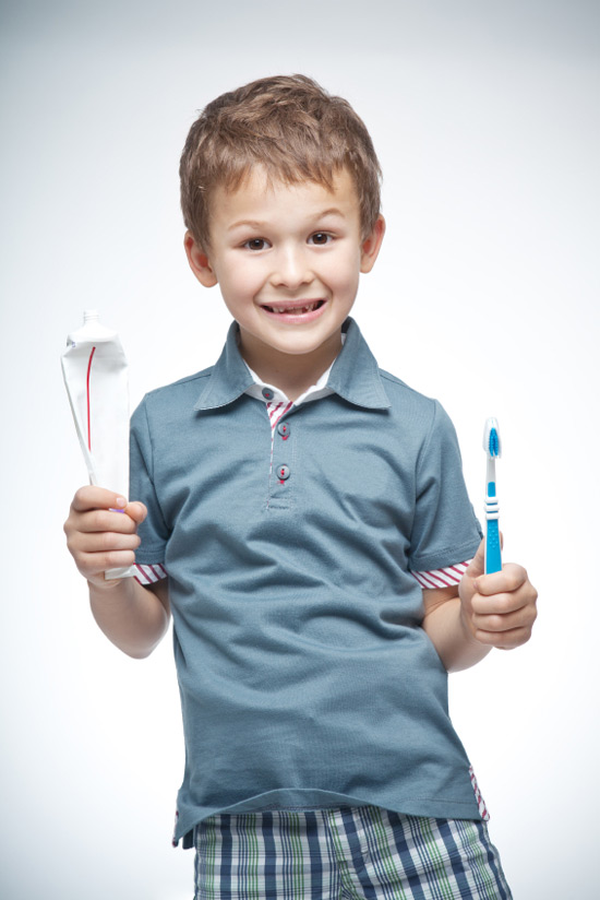 a kid holding toothbrush and tooth paste