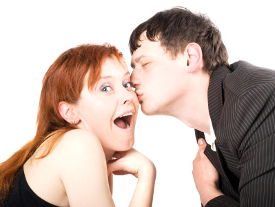 A man dressed in a black suit kissing a woman