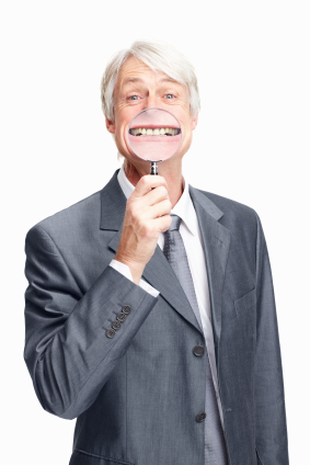 A man wearing a suit holding a magnifying glass on teeth