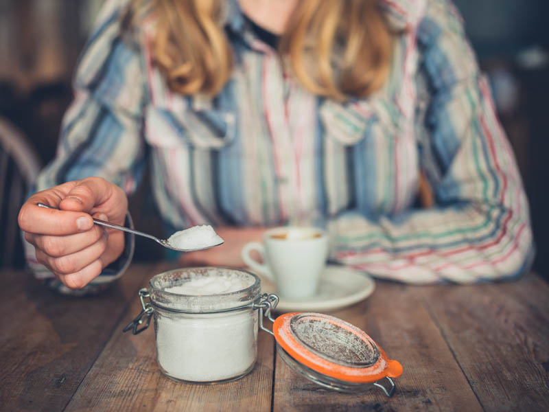 Woman in cafe adding sugar to her coffee