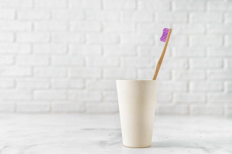 Bamboo toothbrush in eco recycled holder on white background. Zero waste concept