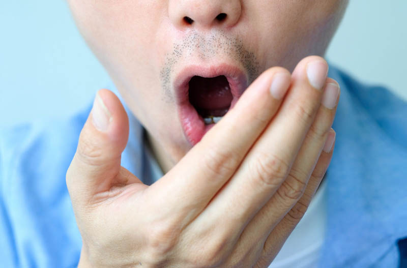 Oral health Men use hands to check for bad breath and breathe.