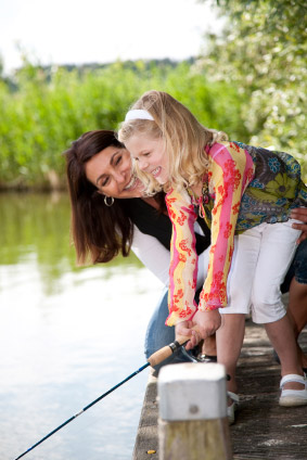 A woman and a girl fishing near the lake