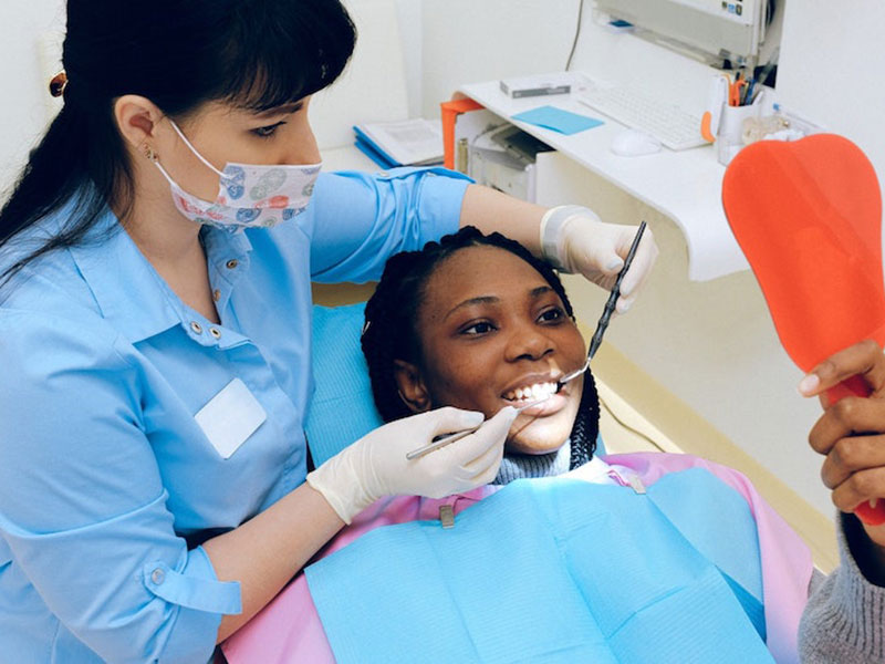 Woman receiving teeth-whitening services from her dental care team.