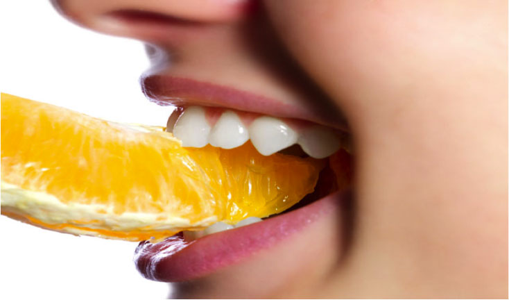 woman chewing on an orange
