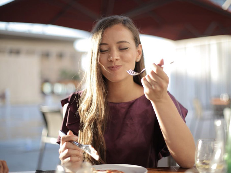 A woman enjoys her dinner on a restaurant patio