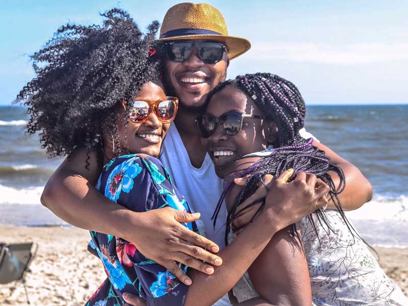 Three people hugging on beach