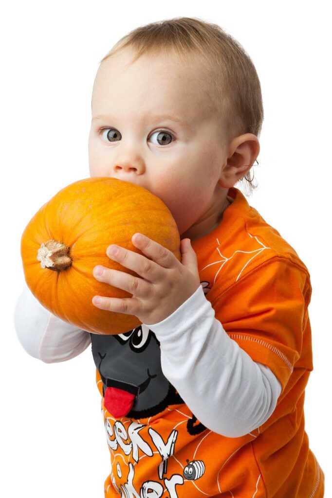 small boy biting pumpkin