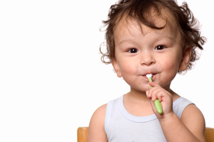 A toddler happily brushes his teeth with a colorful toothbrush