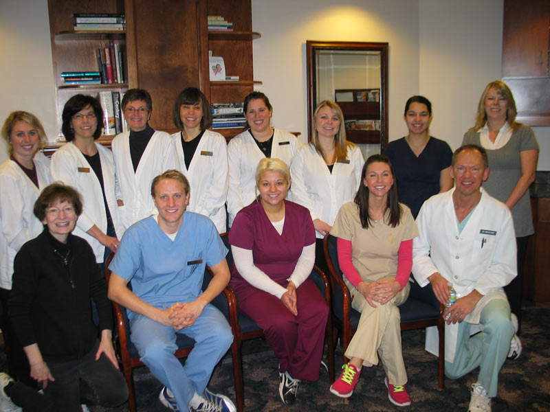A team of professionals in white lab coats, posing together in a scientific research environment.