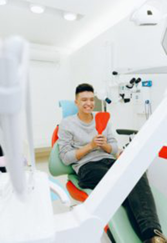 Man looking into a mirror at dentist office.