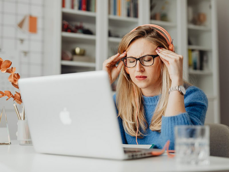 Woman leaning over her computer looking stressed.