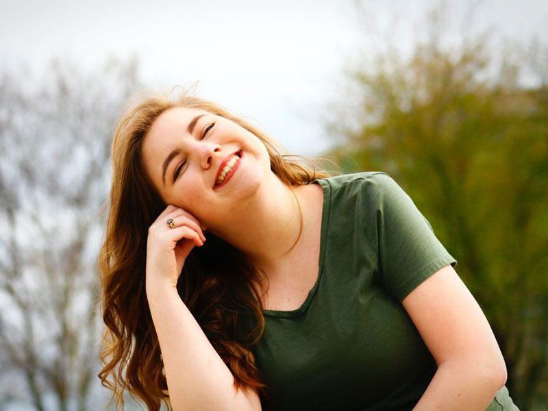 Woman smiling in the sun. Learn if the sun helps whiten your teeth