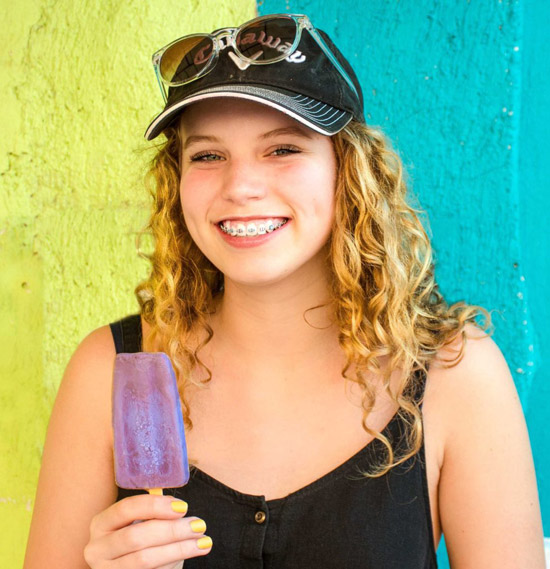 Woman with braces eating a popsicle.
