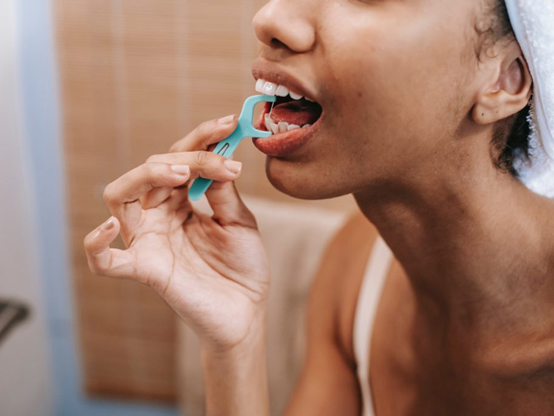 A girl flossing with a floss stick!