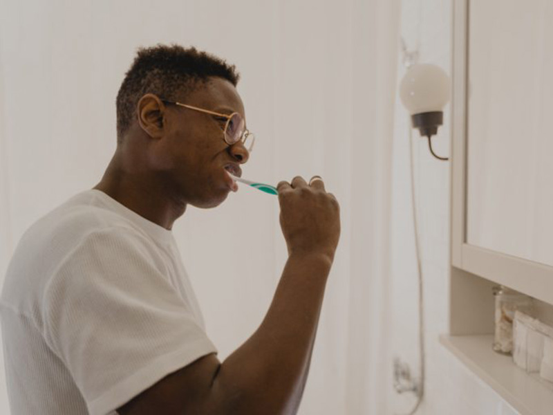 Man in white shirt brushing his teeth.