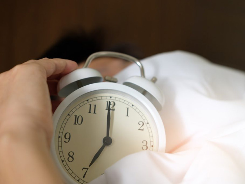 A man sleeping with an alarm clock