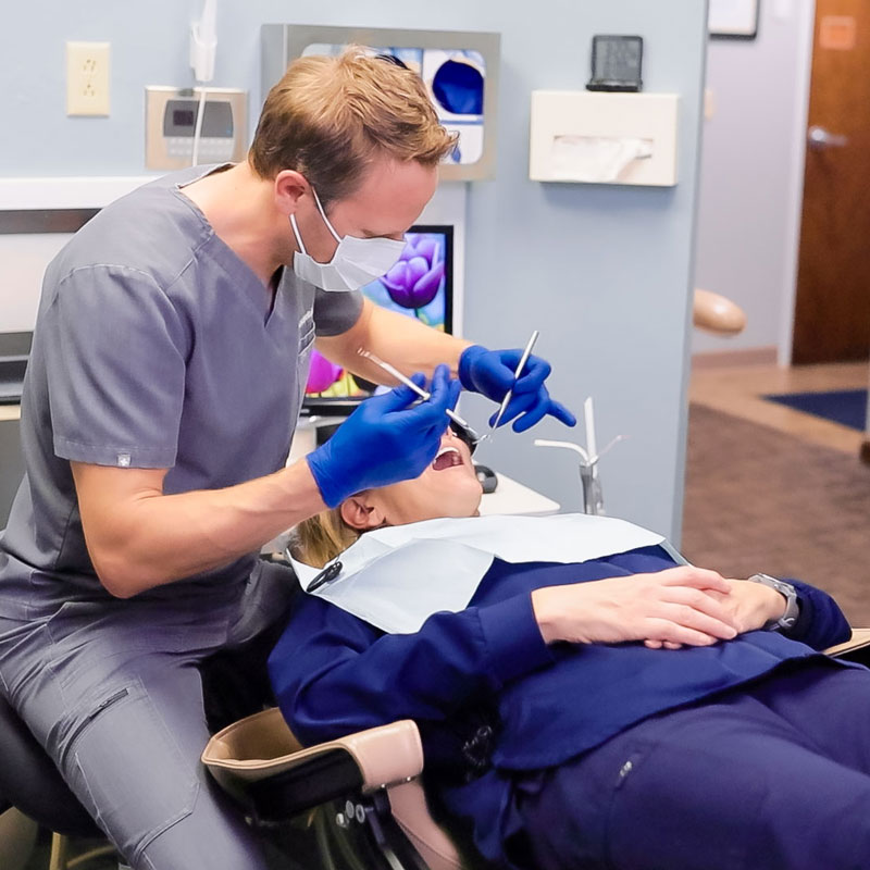 dentist working on patients teeth in dental chair